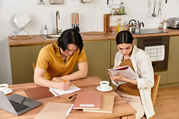 Una coppia amorevole siede a un tavolo di legno nella loro accogliente cucina, lavorando insieme su progetti. — Foto stock