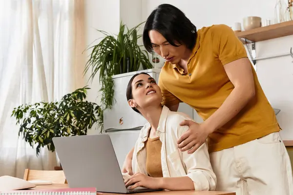 Ein liebendes Paar genießt die Gesellschaft des anderen, während es in seiner gemütlichen Küche am Laptop arbeitet. — Stockfoto
