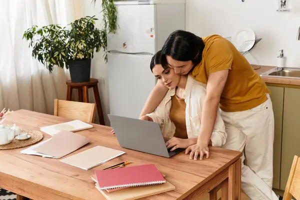 A couple shares affection while focused on a laptop, surrounded by a warm and inviting atmosphere. — Stock Photo