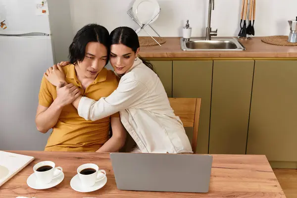 Loving pair sits at a wooden table, sharing smiles and coffee while engaging with a laptop. — Stock Photo
