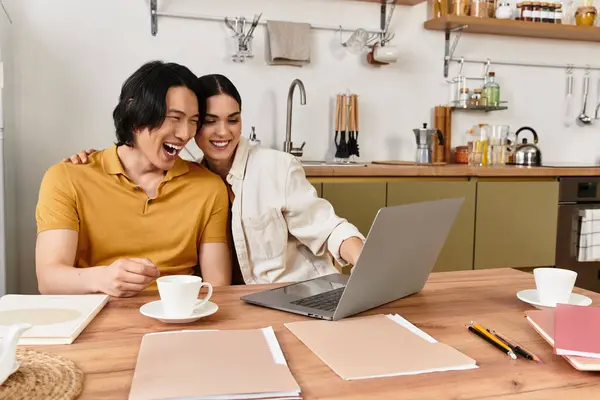 Loving couple enjoys quality time in their cozy kitchen, laughing and exploring new things online. — Stock Photo