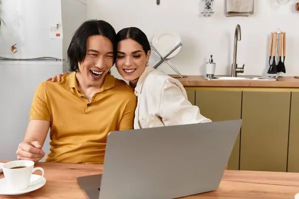 Um casal se senta bem junto, rindo e desfrutando de um momento alegre enquanto usa um laptop em casa. — Fotografia de Stock