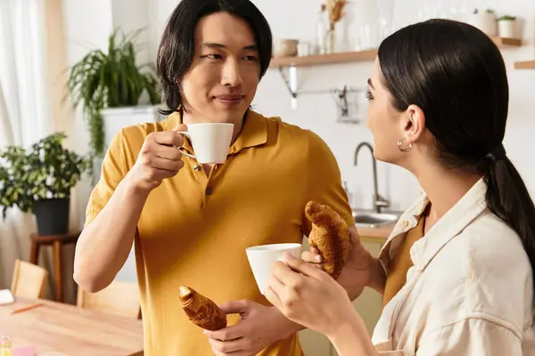 Loving couple enjoys coffee and pastries together in a warm and inviting kitchen setting. — Stock Photo