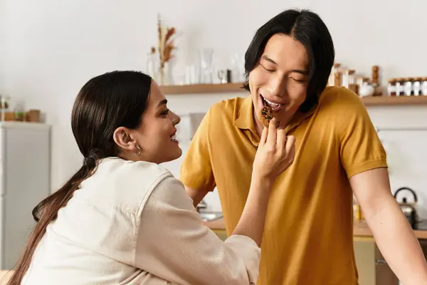 Liebendes Paar genießt einen schönen Moment zu Hause, füttert sich gegenseitig mit Leckereien und lächelt herzlich. — Stockfoto
