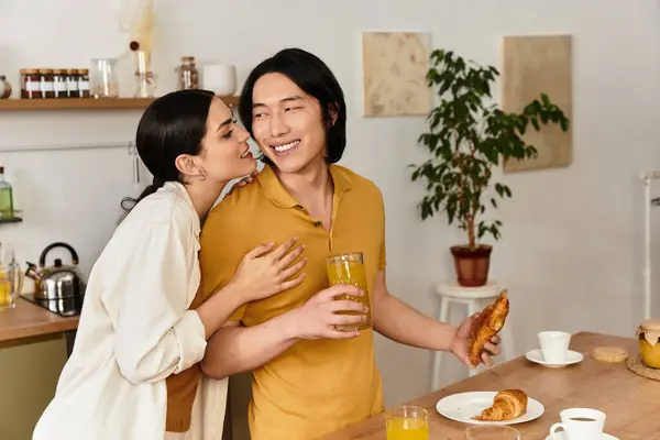 A man and woman share joyful moments during breakfast, savoring pastries and drinks in their home. — Stock Photo