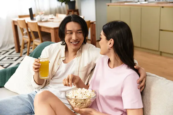 Cuddled on the couch, the couple shares a joyful moment filled with snacks and laughter. — Stock Photo