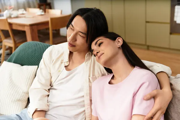 A man and woman relax closely together on a sofa, sharing warmth and affection in their home. — Stock Photo