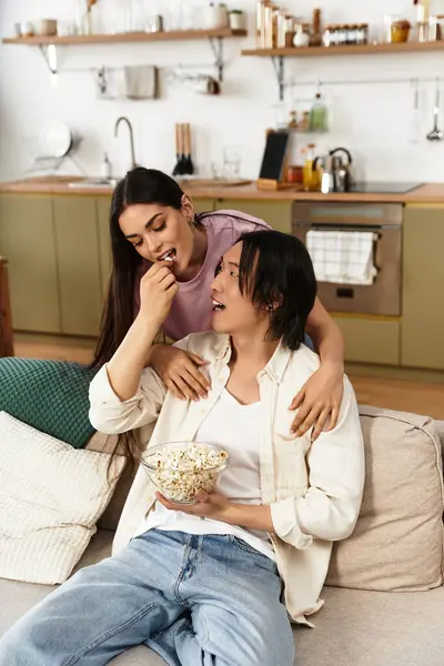 Juntos em sua casa convidativa, um casal gosta de pipocas enquanto se unem e compartilham sorrisos. — Fotografia de Stock