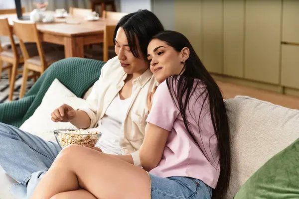 A couple relaxes together on a comfortable couch, sharing popcorn and laughter at home. — Stock Photo