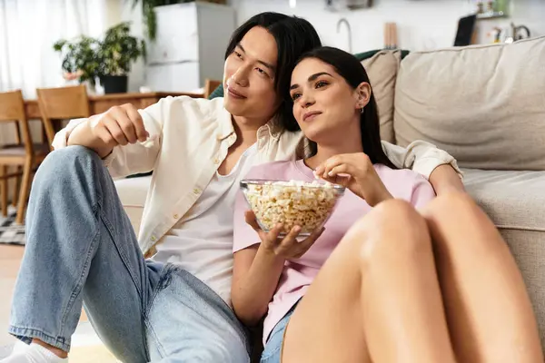 Zwei Menschen teilen einen liebevollen Moment zu Hause, teilen Popcorn und lachen, während sie einen Film ansehen. — Stockfoto