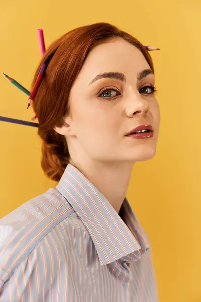 Une jeune femme pose élégamment avec des crayons de couleur dans les cheveux, rayonnant de créativité. — Photo de stock