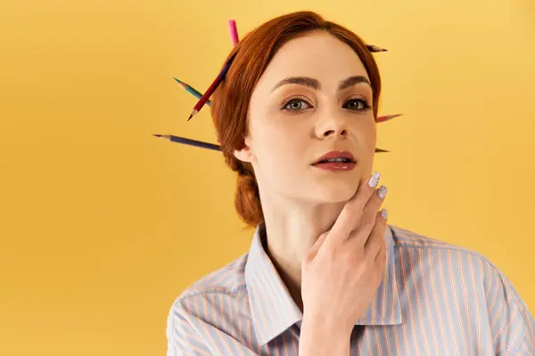 Una joven de pelo rojo posa con lápices vibrantes, mostrando su espíritu artístico. - foto de stock