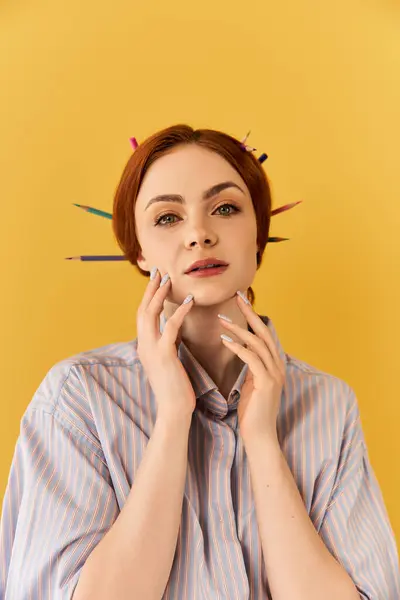 Fiduciosa giovane donna con forniture artistiche colorate nei capelli posa su uno sfondo giallo. — Foto stock