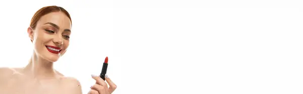 A young woman smiles, holding bright red lipstick in anticipation of her evening plans. — Stock Photo