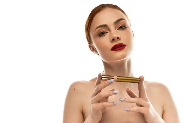 Una hermosa mujer joven sostiene un producto de maquillaje, irradiando sofisticación y estilo en luz brillante. - foto de stock