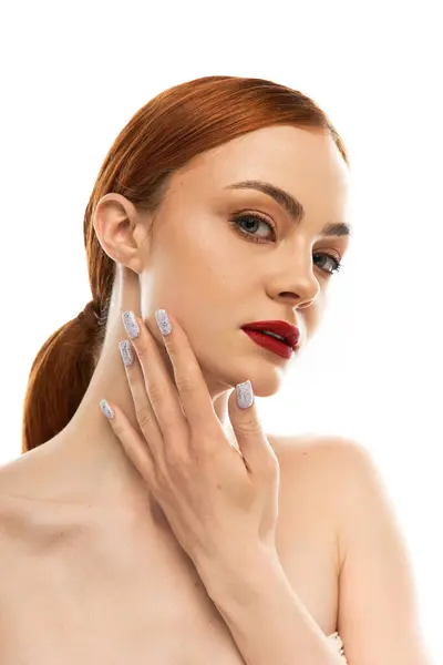 A radiant young woman playfully touches her face while showcasing stylish nail art. — Stock Photo