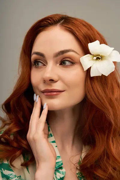 A radiant young woman with flowing red hair smiles, adorned with a lovely flower. — Stock Photo