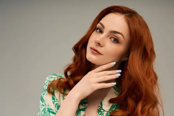 A beautiful young woman with flowing red hair showcases her style and grace while posing gracefully. — Stock Photo