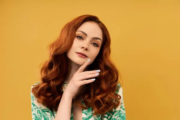 Una bella donna con i capelli rossi ricci si tocca il mento, guardando pensieroso lo spettatore. — Foto stock