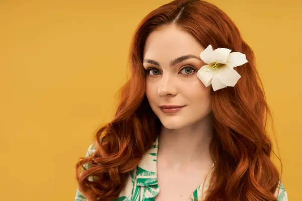 Young woman with beautiful red hair enjoys a cheerful moment, a white flower accenting her style. — Stock Photo