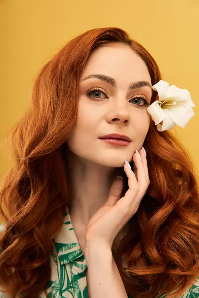 A stunning woman with long red hair holds her hand gently on her face, adorned with a white flower. — Stock Photo