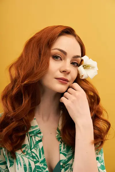 A lovely young woman with flowing red hair gently touches her face while a flower adorns her hair. — Stock Photo