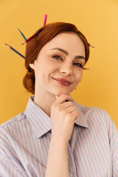 Eine fröhliche junge Frau posiert vor hellem Hintergrund spielerisch mit Bleistiften im Haar. — Stockfoto