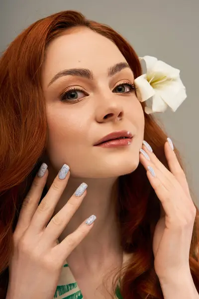 Junge Frau berührt ihr Gesicht sanft, geschmückt mit einer weißen Blume im Haar, die Zuversicht ausstrahlt. — Stockfoto