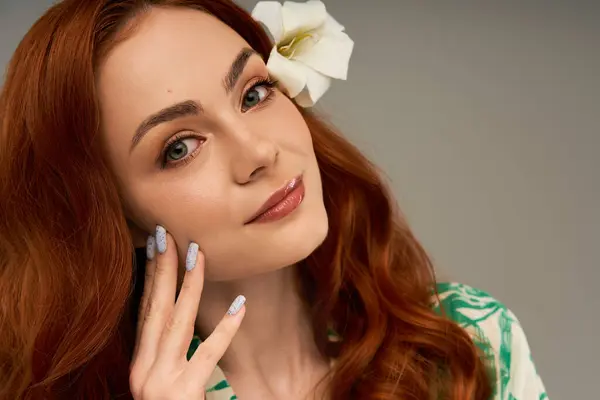 A graceful young woman with vibrant hair poses elegantly, adorned with a delicate flower. — Stock Photo