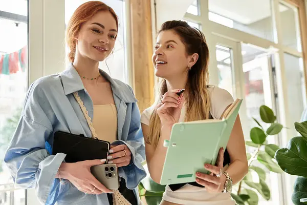 Due giovani donne alla moda condividono momenti gioiosi mentre discutono idee in un caffè. — Foto stock