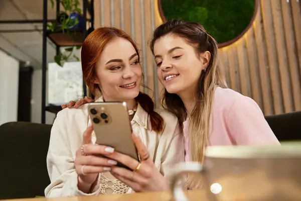 Beautiful friends enjoy laughter and connection while exploring their smartphone together. — Stock Photo