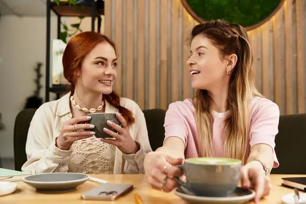Friends share laughter and coffee in a cozy, contemporary cafe setting. — Stock Photo