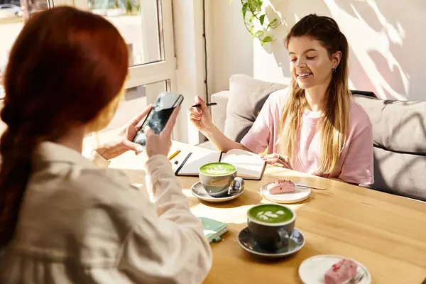 Two young women enjoy their time together in a modern cafe, savoring treats and drinks. — Stock Photo
