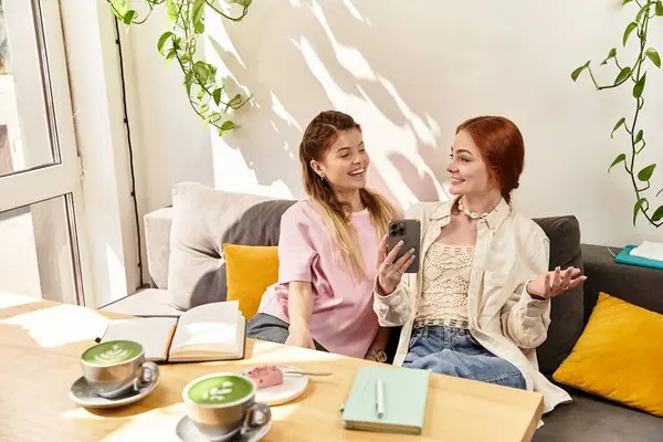 Two young women share laughs and stories in a cafe — Stock Photo