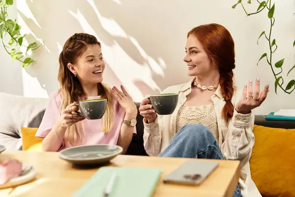 Two young women share laughs and stories over matcha latte in a trendy cafe setting. — Stock Photo