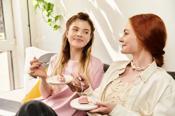 Due giovani donne condividono risate e deliziose torte mentre si rilassano insieme in un caffè chic. — Foto stock