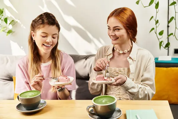 Zwei junge Frauen genießen köstliche Desserts und schwungvolle Drinks in schicker Café-Atmosphäre. — Stockfoto