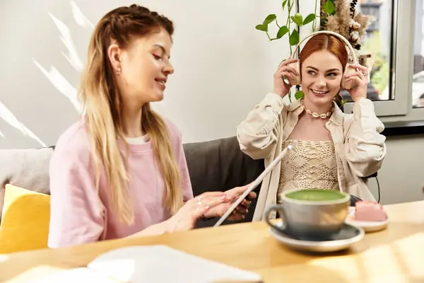 Duas lindas jovens mulheres desfrutam da companhia uma da outra enquanto bebem bebidas e compartilham risos. — Fotografia de Stock
