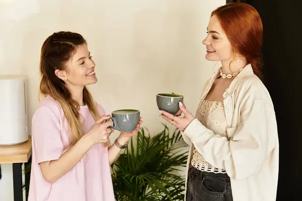 Two friends enjoy warm drinks while chatting and laughing in a trendy cafe atmosphere. — Stock Photo