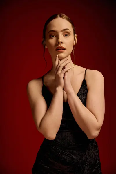 Una joven posa graciosamente en un elegante vestido negro, encarnando la elegancia con una mirada cautivadora. - foto de stock
