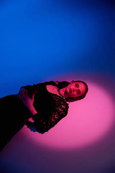 Une belle jeune femme présente une tenue chic sur fond rose et bleu frappant. — Photo de stock