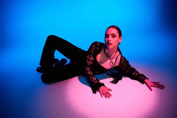 A stylish young woman relaxes in a vibrant studio, dressed in fashionable attire. — Stock Photo