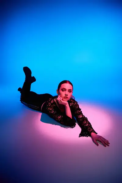 A beautiful young woman showcases a stylish outfit while lying against a colorful backdrop. — Stock Photo