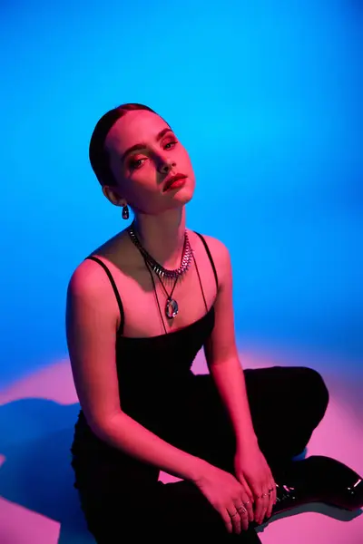 A young woman flaunts her stylish outfit against a bright blue and pink backdrop. — Stock Photo