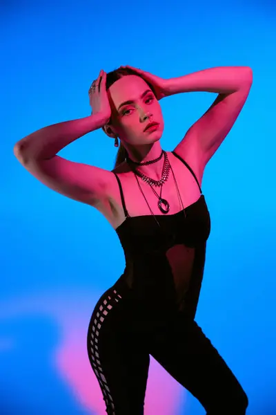 A beautiful young woman poses gracefully in a stylish outfit. Pink lighting adds a vibrant touch. — Stock Photo