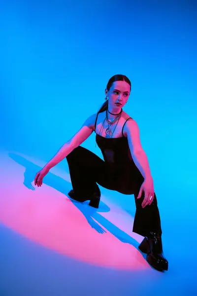 Une belle jeune femme présente une tenue chic dans un studio rempli de lumière rose et bleue. — Photo de stock