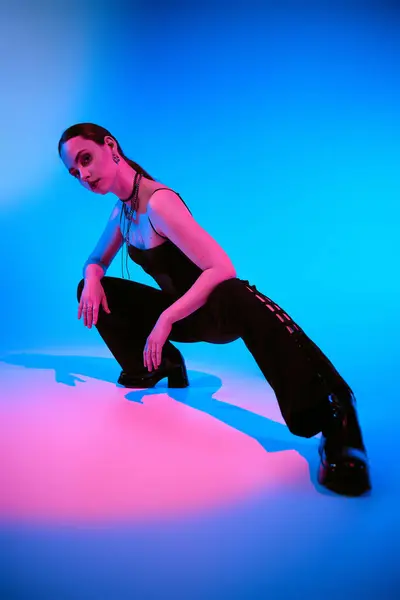 A stylish young woman strikes a dynamic pose, bathed in pink light. — Stock Photo
