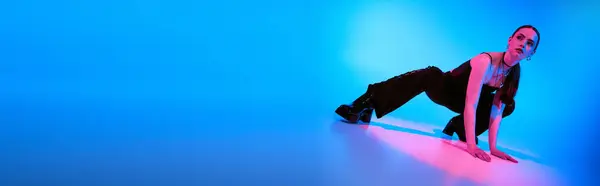 A young woman strikes a stylish pose amid vibrant blue and pink lights, banner — Stock Photo