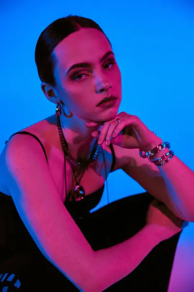 Una hermosa joven muestra su sentido de la moda en un traje llamativo contra un telón de fondo azul. — Stock Photo