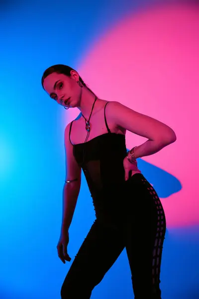 A beautiful young woman models a chic outfit in a studio, surrounded by vibrant colors. — Stock Photo